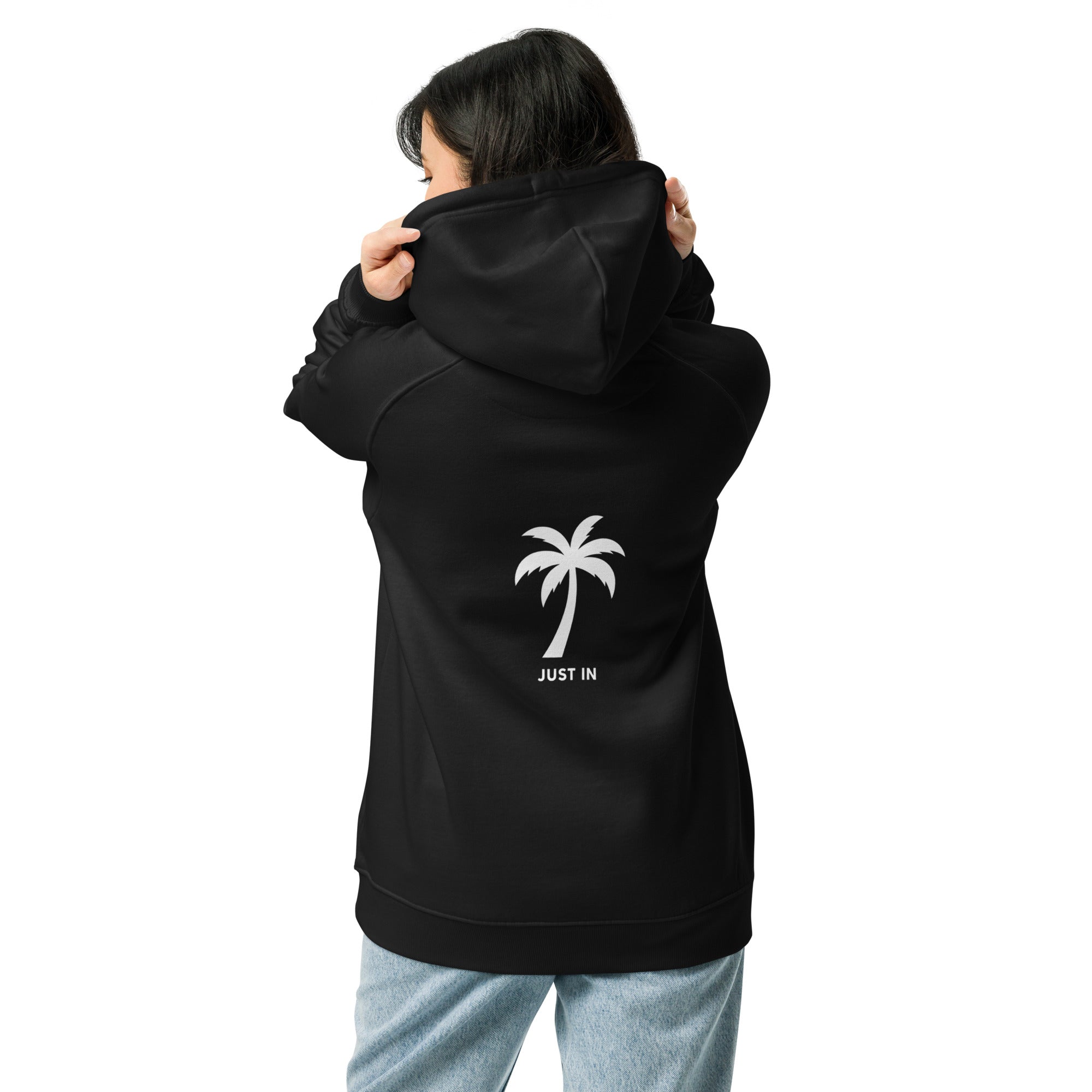 Frau trägt schwarzen Hoodie, zeigt Rückseite mit JUST IN Palmenprint